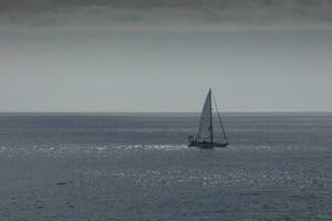 Sailboat with sail unfurled, sailing on the calm sea at sunset. photo
