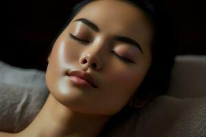 Asian woman applies skin tonic to cheek with closed eyes photo