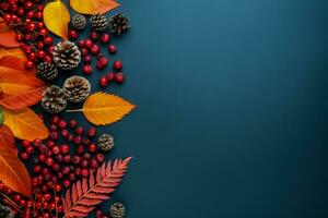 Colorful red and yellow autumn leaves cones and rowan berries on trendy indigo green background photo