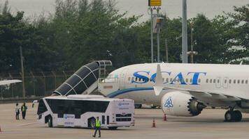 phuket, Tailandia febrero 25, 2023 - boeing 737 max de largarse aerolíneas en delantal a phuket aeropuerto. tablero llegada. escalera unión cósmica con el aeronave. delantal autobús esperando para pasajeros video