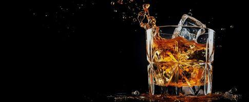 Isolated on black a Glass splashes Whiskey with ice cubes photo