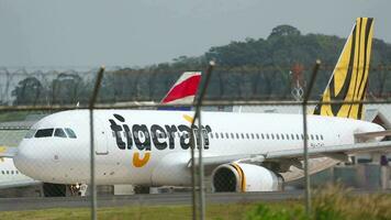 phuket, thailand november 27, 2015 - flygbuss a320, 9vtao av tigerair taxning på de bana på phuket flygplats. trafik. flygplan på de taxibana. se av de flygfält genom de staket video