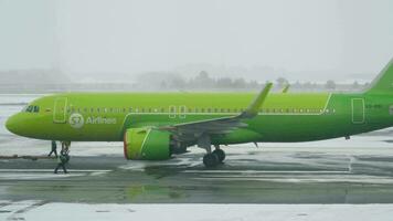 NOVOSIBIRSK, RUSSIAN FEDERATION NOVEMBER 14, 2020 - Airbus A320 271N, VQ BRI of S7 Airlines pulls a tractor in a snowy airport to the Tolmachevo terminal, Novosibirsk. Airport in winter video