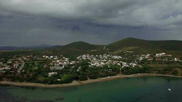 Flying over sea, beach and cottages in resort town of Greece on overcast day video