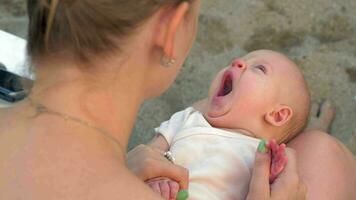 soñoliento bebé niña acostado en madres regazo al aire libre video