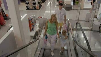 jovem família com criança equitação escada rolante dentro compras Centro video