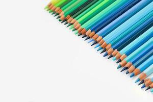 Multi-colored pencils lie on a white table, the blue range of colors photo