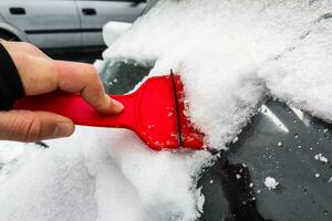 Cleaning the car from snow with a scraper photo