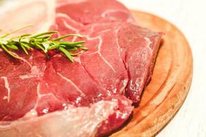 Fresh piece of meat large beef steak on the bone ossobuco with rosemary sprig. photo