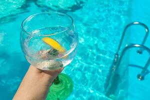 Cocktail with lemon tonic on blue pool background photo