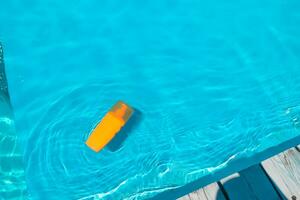 Spray sunscreen stands on the background of the pool photo