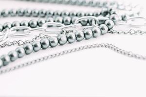A necklace of gray beads with chain decorations on a white aesthetic background. photo