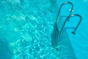 Staircase in the swimming pool with blue water in the background photo