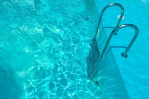 Staircase in the swimming pool with blue water in the background photo