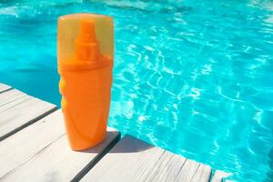 Spray sunscreen stands on the background of the pool photo