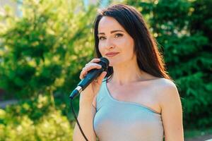 mujer vocalista con oscuro pelo en un vestir canta dentro un micrófono foto