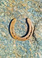 A rusty horseshoe on a stone background texture. photo