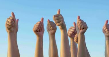 Hands with thumbs up raised against blue sky video