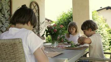 två barn äter sallad på en tabell utanför video