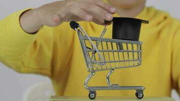 a person holding a shopping cart with a graduation cap on top video