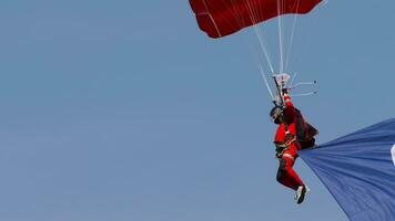 phuket, Tailândia novembro 28, 2019 - paraquedista dentro vermelho uniforme desce. paraquedista dentro a azul céu. extremo entretenimento para turistas às mar video