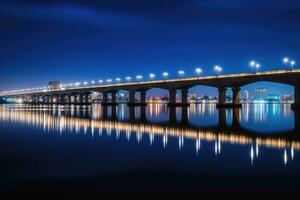 A low angle nightshot of a bridge with a skyline in the background.AI generative photo