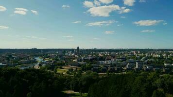 ver de el horizonte de Vilnius ciudad mediante el arboles de el parque a puesta de sol video