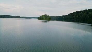 el cámara se mueve a través de el superficie de el lago a un isla en el distancia. asveja es el mas largo lago en Lituania video