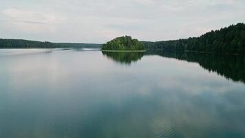 el cámara se mueve lejos desde el isla a lo largo el superficie de el agua. asveja es el mas largo lago en Lituania video