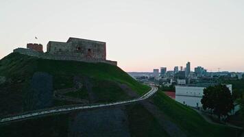 The camera pans up from below with a view of Gediminas Tower and the center of Vilnius at sunset video