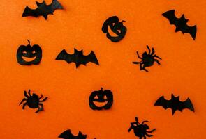 Halloween background, paper black bats, pumpkins and spiders on orange paper. photo