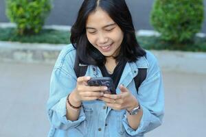 carefree smiling stylish asian young woman using smartphone app, video chat, online shop, and browsing social media wear casual in outdoor photo