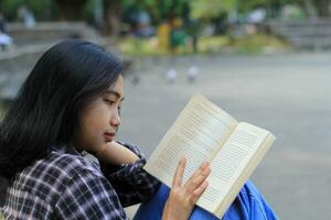 happy mindful young asian woman college student reading a book in the park, education concept photo