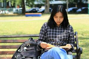 joven mujer asiático estudiante leer un Nota libro seriamente a preparar examen foto