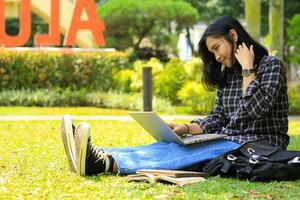 young smiling asian woman using laptop and writing notebook, cheerful asian student watching webinar and studying from e course photo