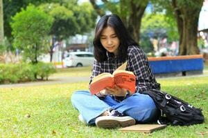 happy mindful young asian woman college student reading a book in the park, education concept photo