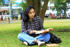 thoughtful woman asian student reading a book and thinking to planning a project photo