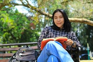 contento alegre asiático hembra estudiante leyendo un libro y riendo disfrutando vacaciones foto