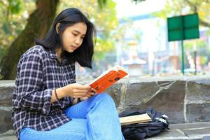 serious asian woman student read a book think and do research for her homework photo