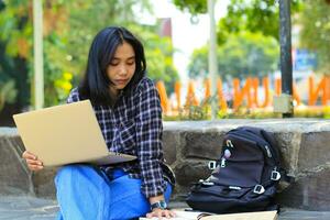 young smiling asian woman using laptop and writing notebook, cheerful asian student watching webinar and studying from e course photo