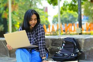 young smiling asian woman using laptop and writing notebook, cheerful asian student watching webinar and studying from e course photo