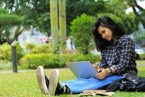 young smiling asian woman using laptop and writing notebook, cheerful asian student watching webinar and studying from e course photo
