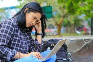 exhausted and stressed asian woman student working using laptop and study with text books in outdoors photo