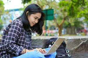 relax asian young woman smiling using laptop working freelance and happy get e commerce offer photo