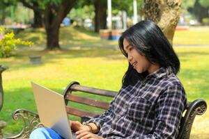 relax asian young woman smiling using laptop working freelance and happy get e commerce offer photo