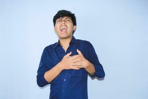 asian man office worker screaming and touching his chest suffering from heart attack pain wearing navy shirt, isolated white photo