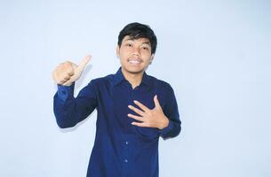 proud young asian man smiling with grateful face for survived from heart attack and has recovery is holding chest with thunbs up wearing navy shirt photo