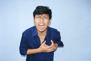 asian man office worker screaming and touching his chest suffering from heart attack pain wearing navy shirt, isolated white photo