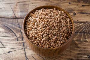 Buckwheat raw in a wooden bowl on a rustic wooden background. photo