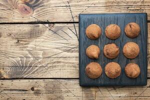 Delicious chocolate truffles sprinkled with cocoa powder on a wooden stand. Wooden background. Copy space. photo